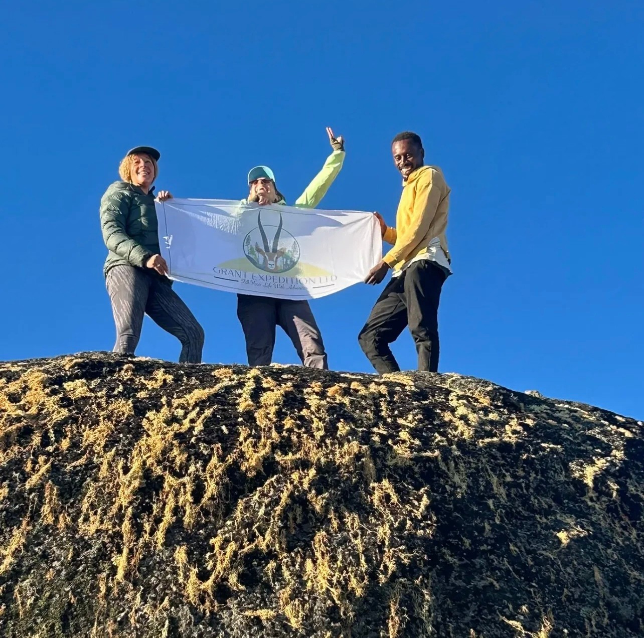 Kilimanjaro climbing team holding a Grant Expedition banner